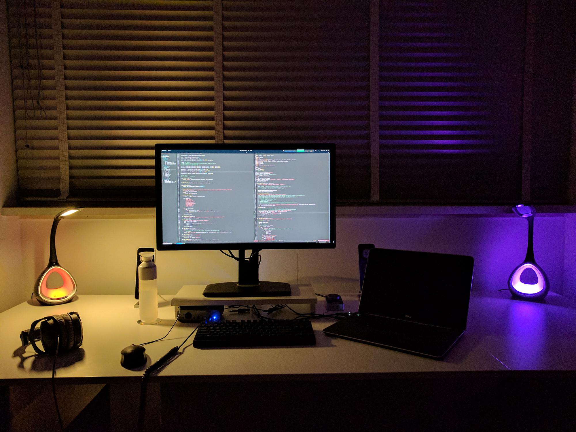 Clean desk with monitor, laptop, two colourful led lights, headphones